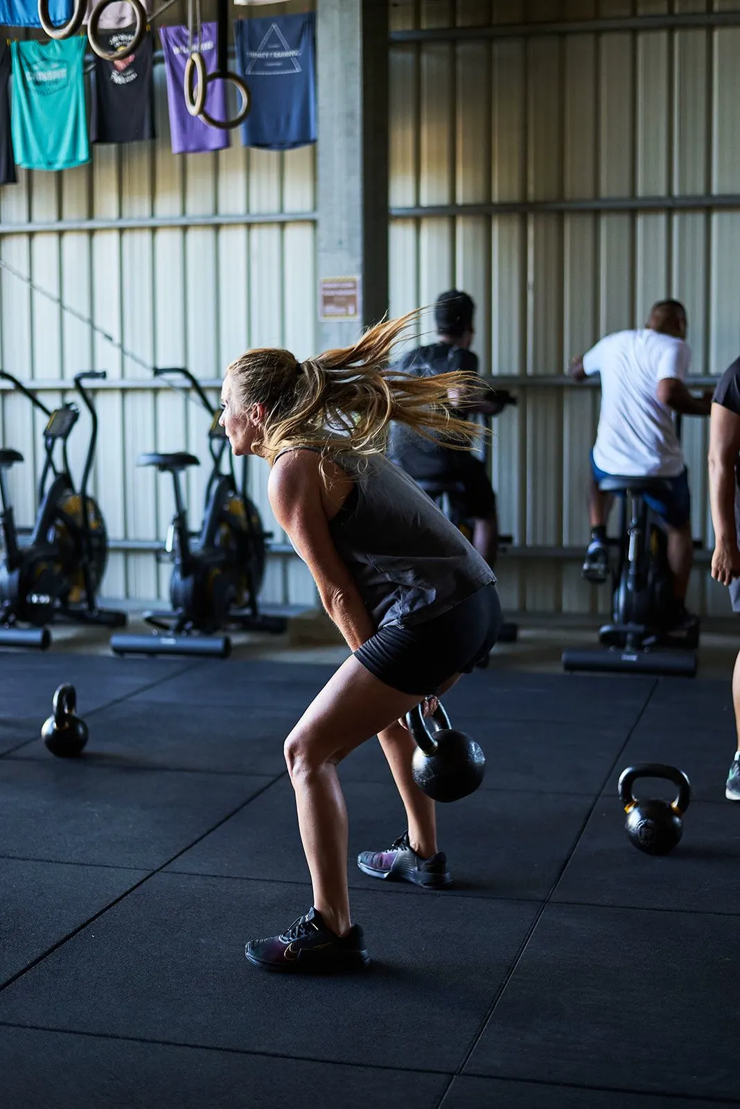 Un swing de kettlebell à l'intérieur, les vélos alignés en arrière-plan.