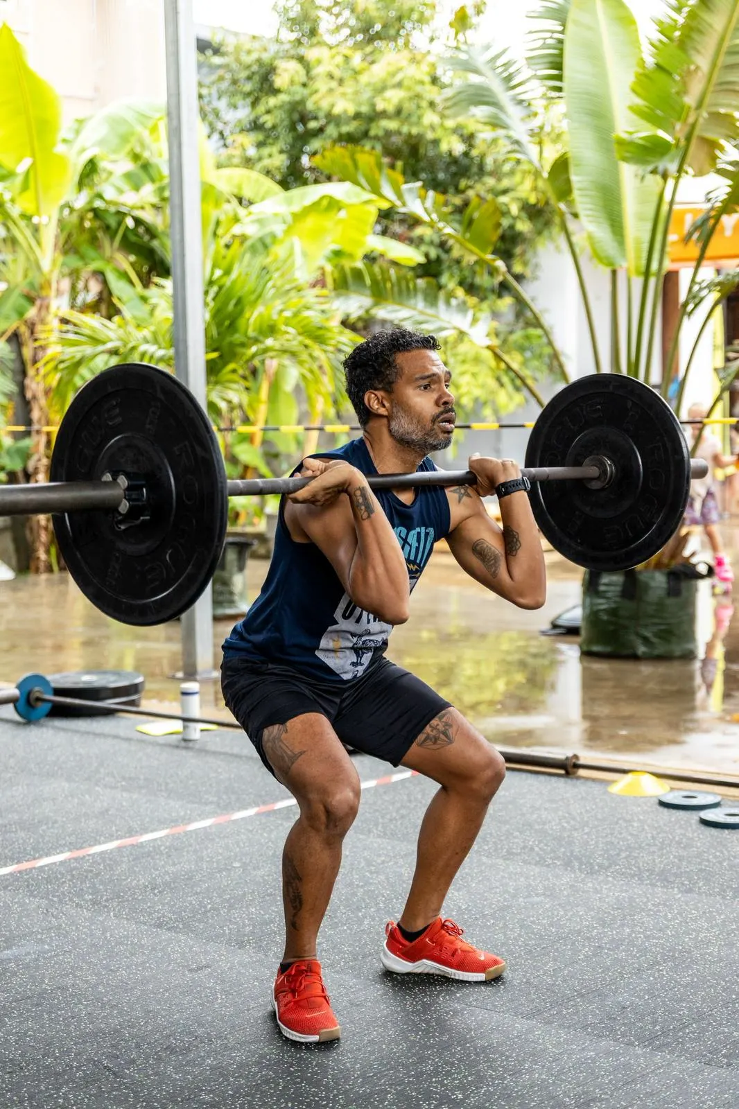 Un athlète au plus bas d'un front squat, dehors, la barre chargée sur les épaules.